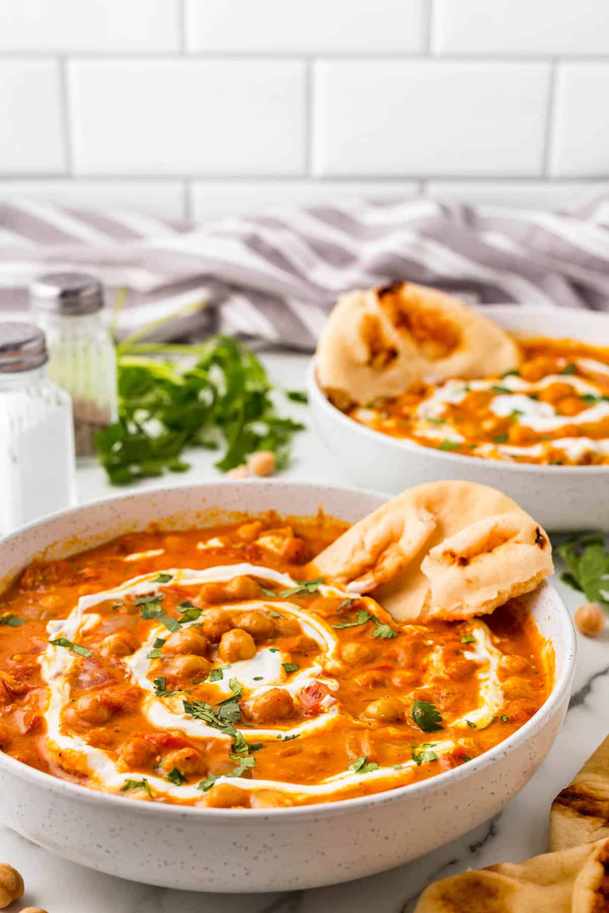 Bowls of chickpea curry with naan bread stuck in. 