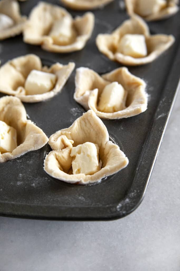 Adding in brie to the crescent roll. 