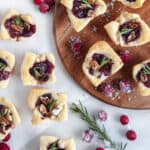 Overhead shot of cranberry brie bites with sugared cranberries and a rosemary sprig scattered around.