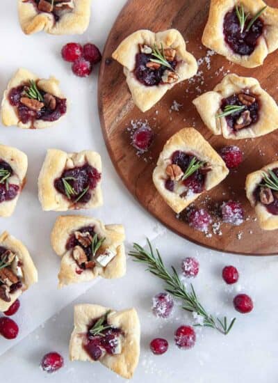 Overhead shot of cranberry brie bites with sugared cranberries and a rosemary sprig scattered around.