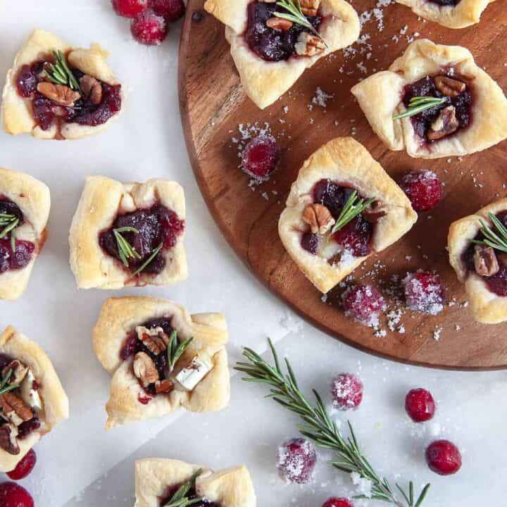 Overhead shot of cranberry brie bites with sugared cranberries and a rosemary sprig scattered around.