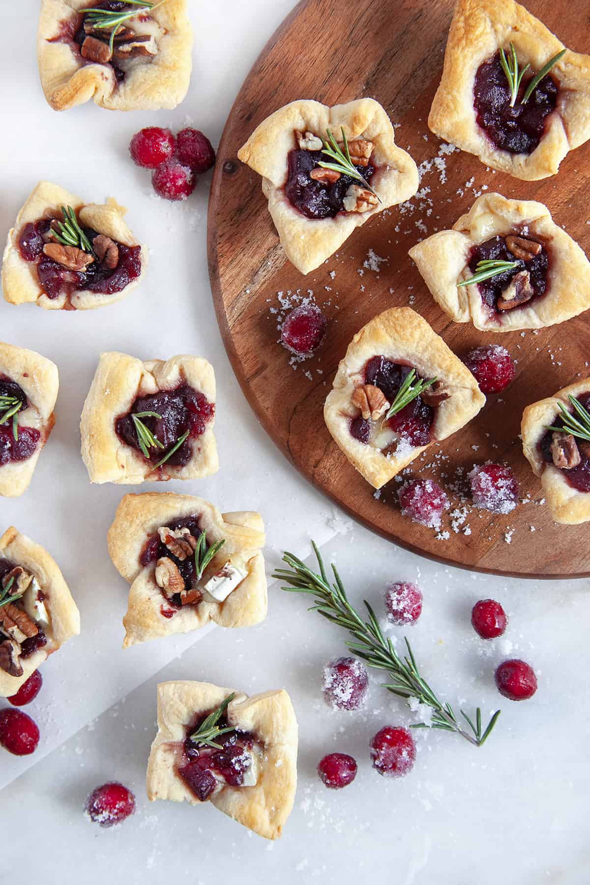 Overhead shot of cranberry brie bites with sugared cranberries and a rosemary sprig scattered around. 