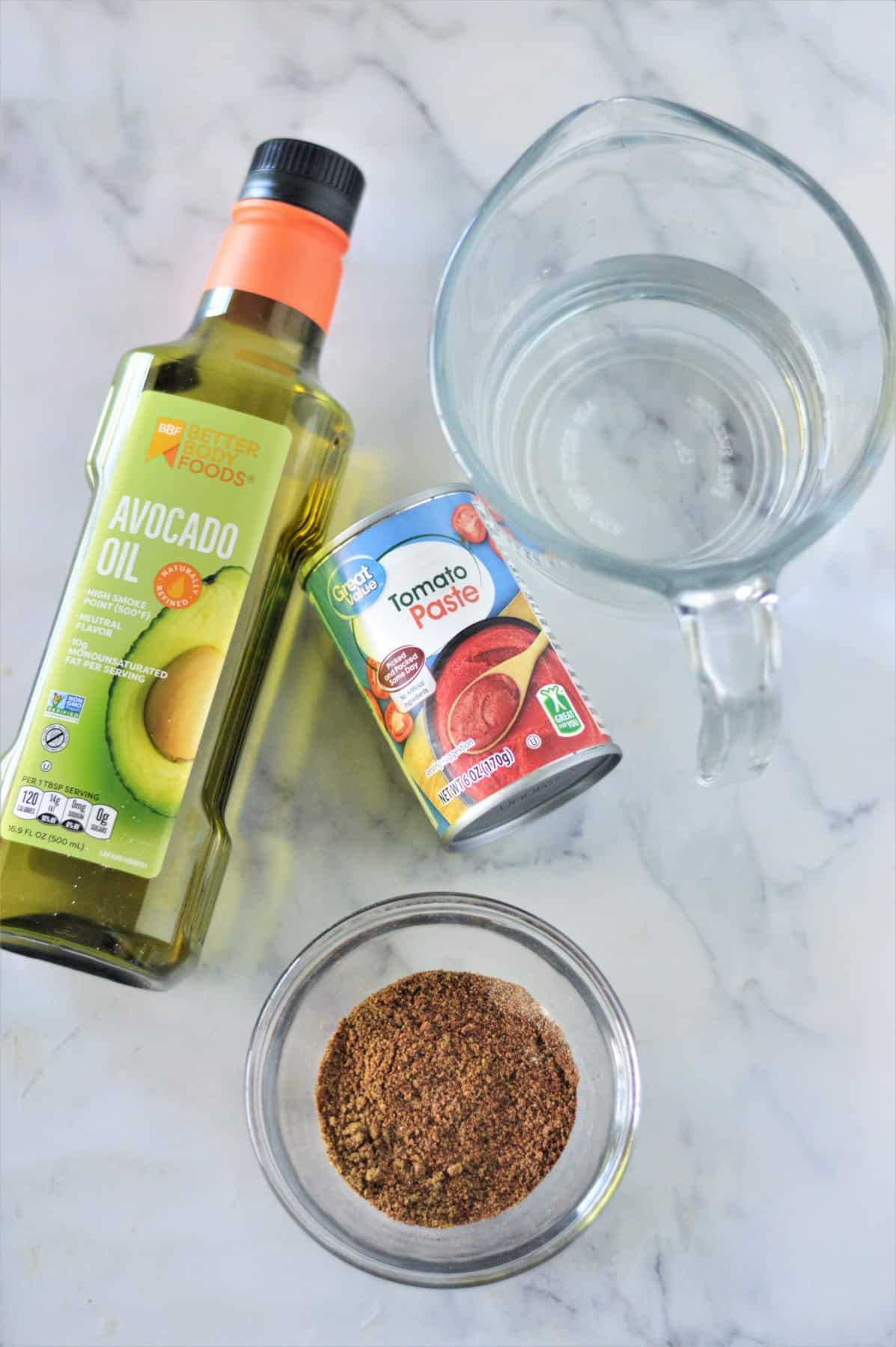 Ingredients needed to make homemade enchilada sauce on a marble countertop.