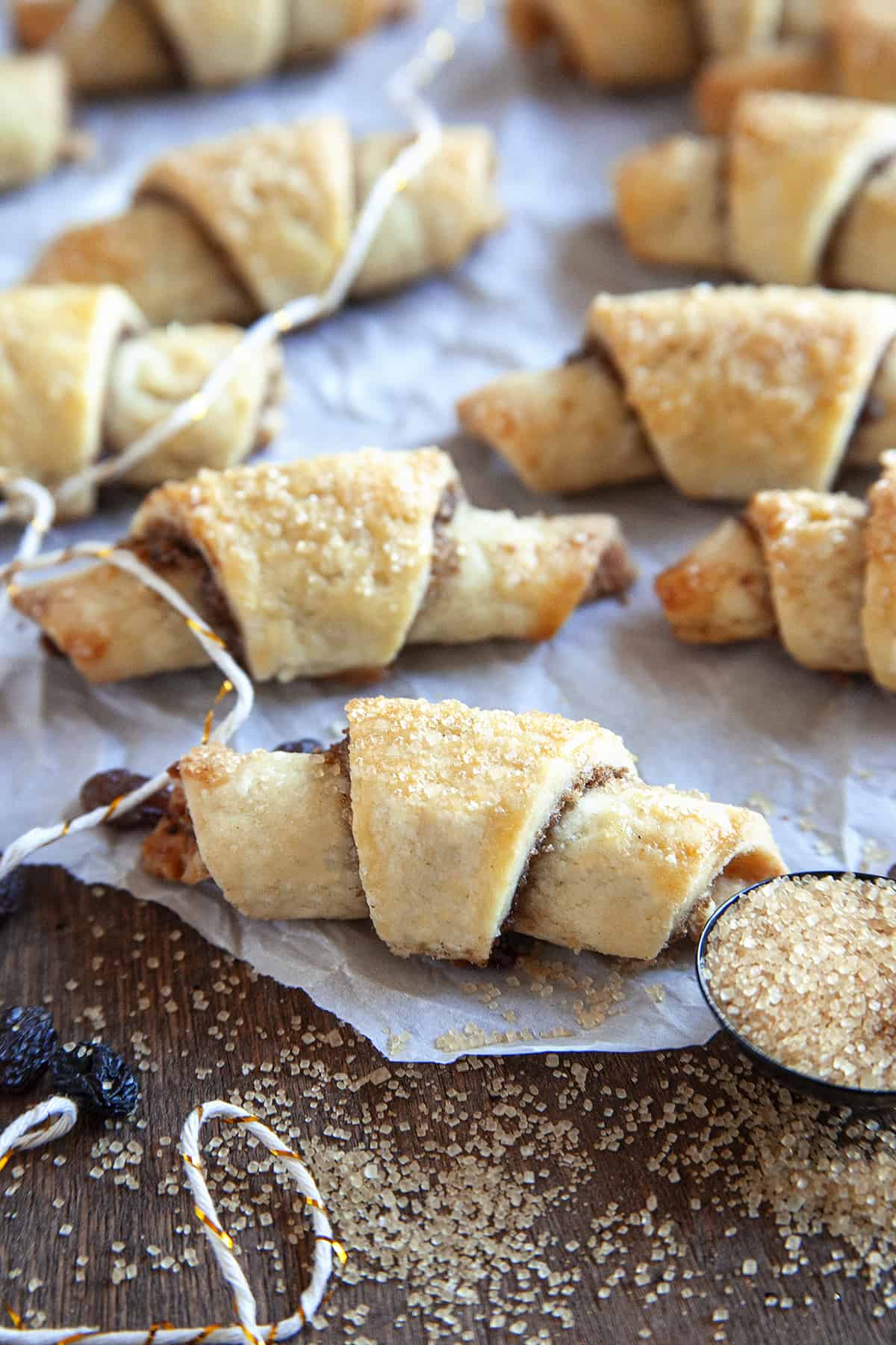 Rugelach with scattered sugar on parchment with raisins and string. 