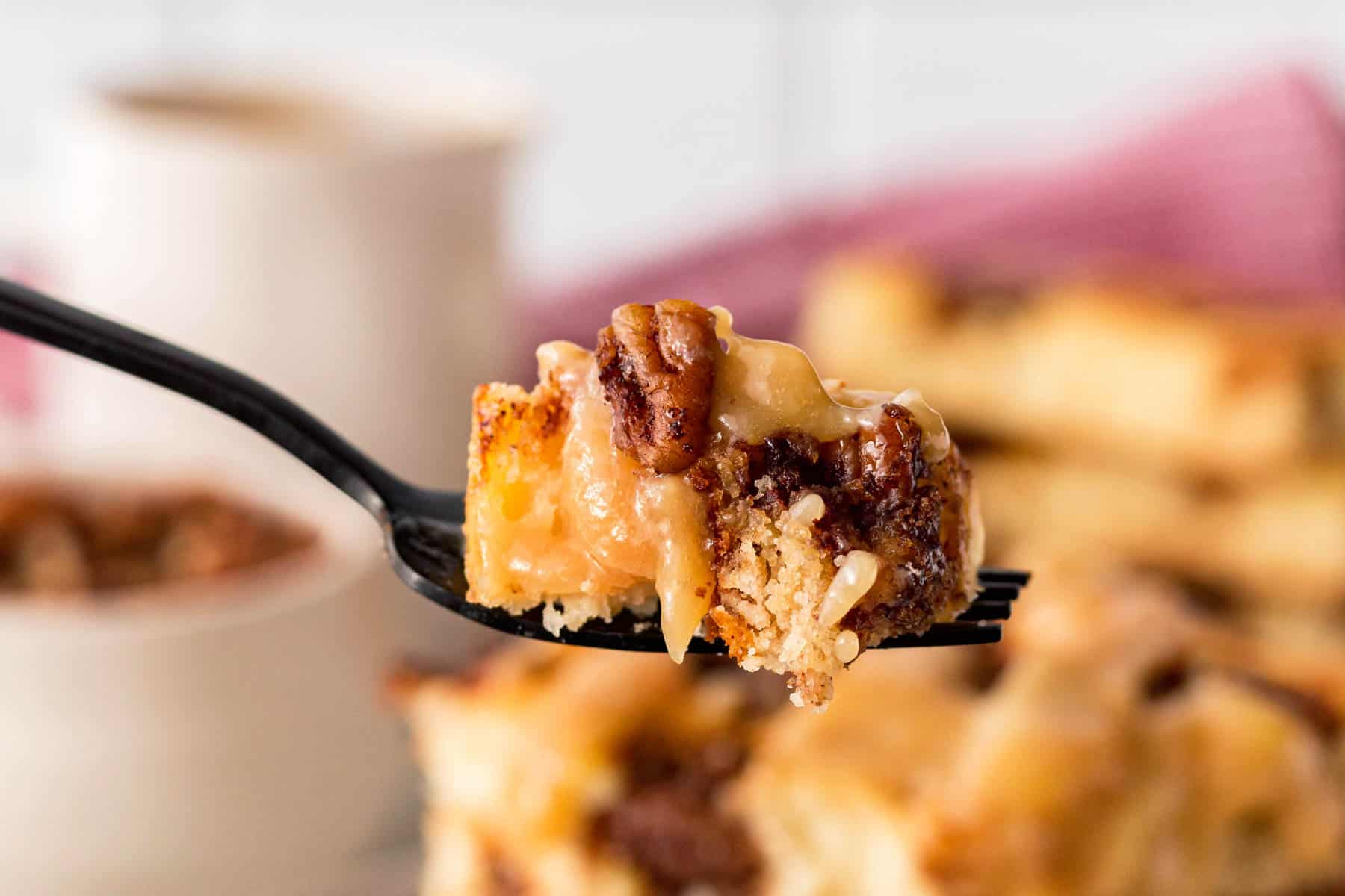 Horizontal photo of maple pecan pancake with glaze on a fork. 