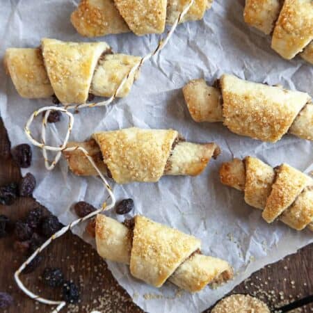 Overhead shot of rugelach on parchment with raisins scattered.