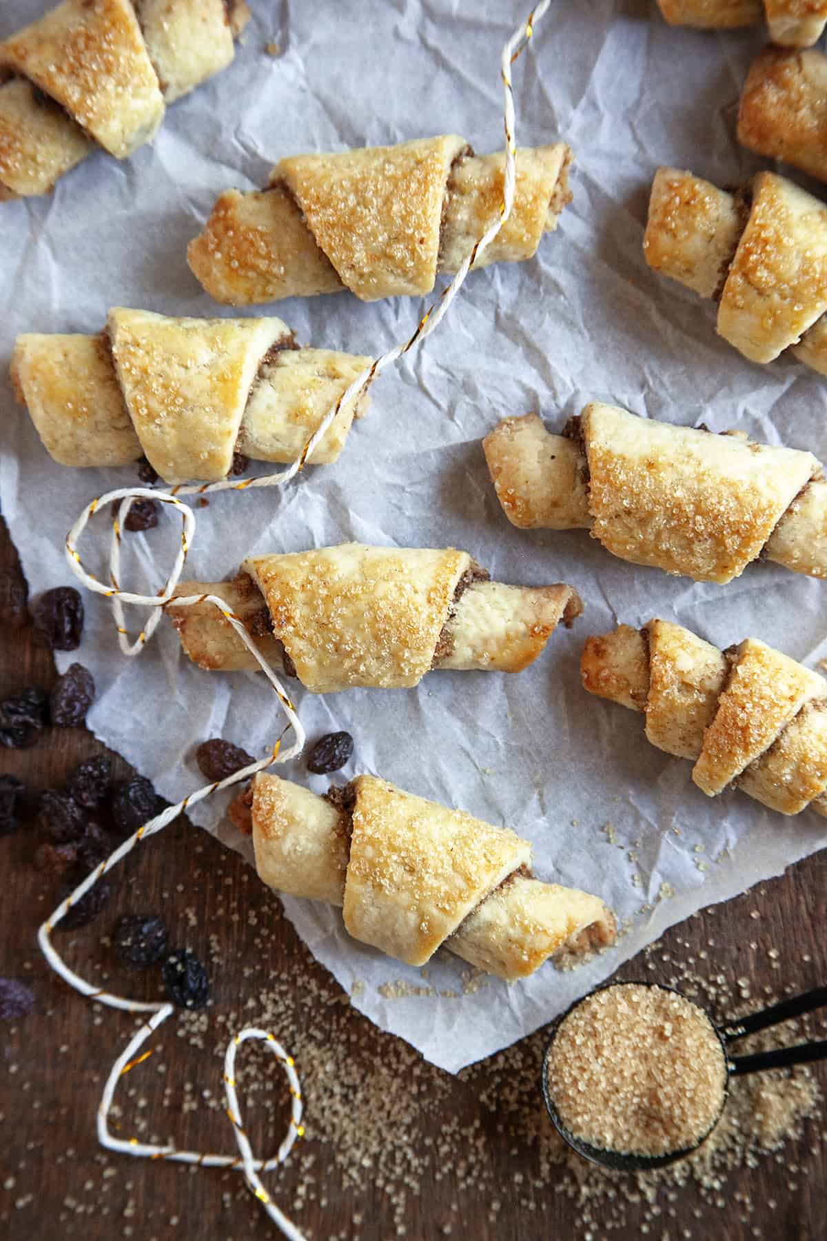 Overhead shot of rugelach on parchment with raisins scattered. 