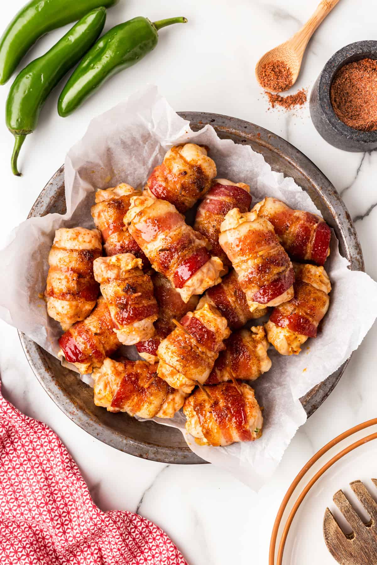 Overhead plate of Bacon-wrapped Chicken Bites on parchment paper on a metal plate. 