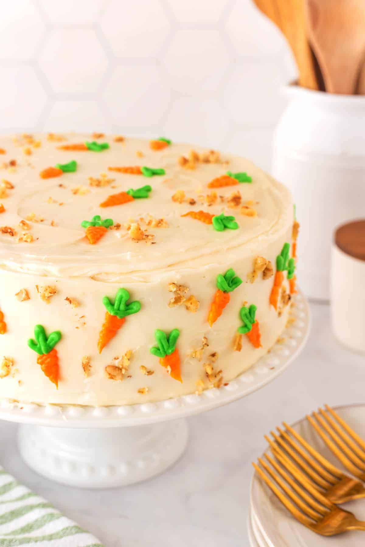 Carrot cake on a cake stand, decorated with carrots and nuts. 