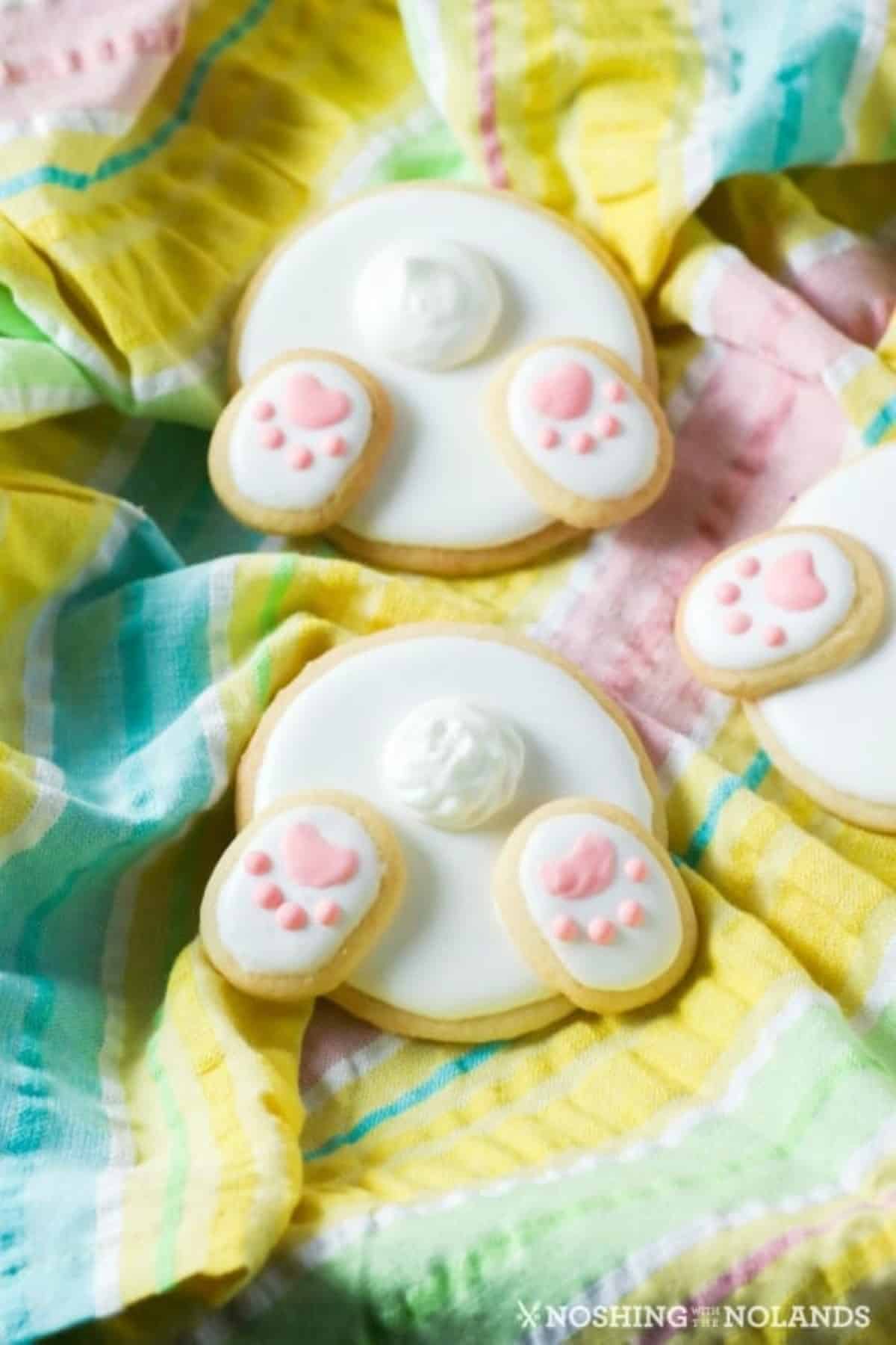 Bunny bum cookies on a tea towel made of light pastel Easter colors. 