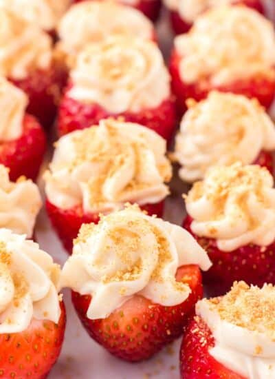 Close-up of cheesecake stuffed strawberries on a white plate.