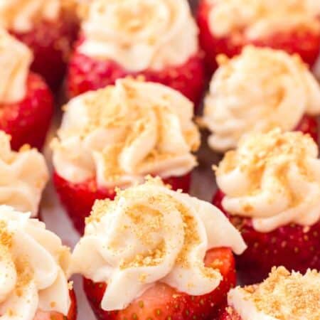 Close-up of cheesecake stuffed strawberries on a white plate.