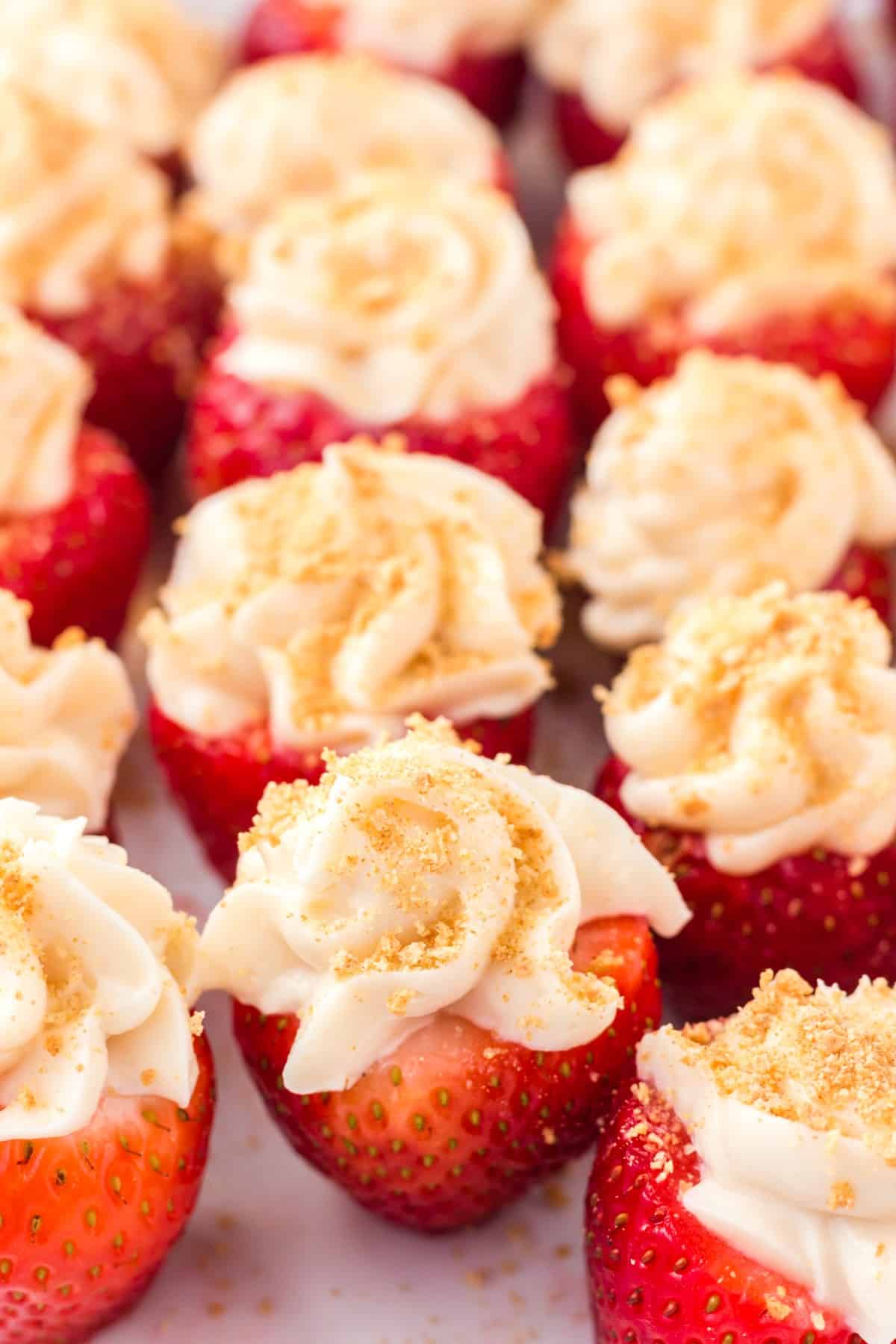 Close-up of cheesecake stuffed strawberries on a white plate. 