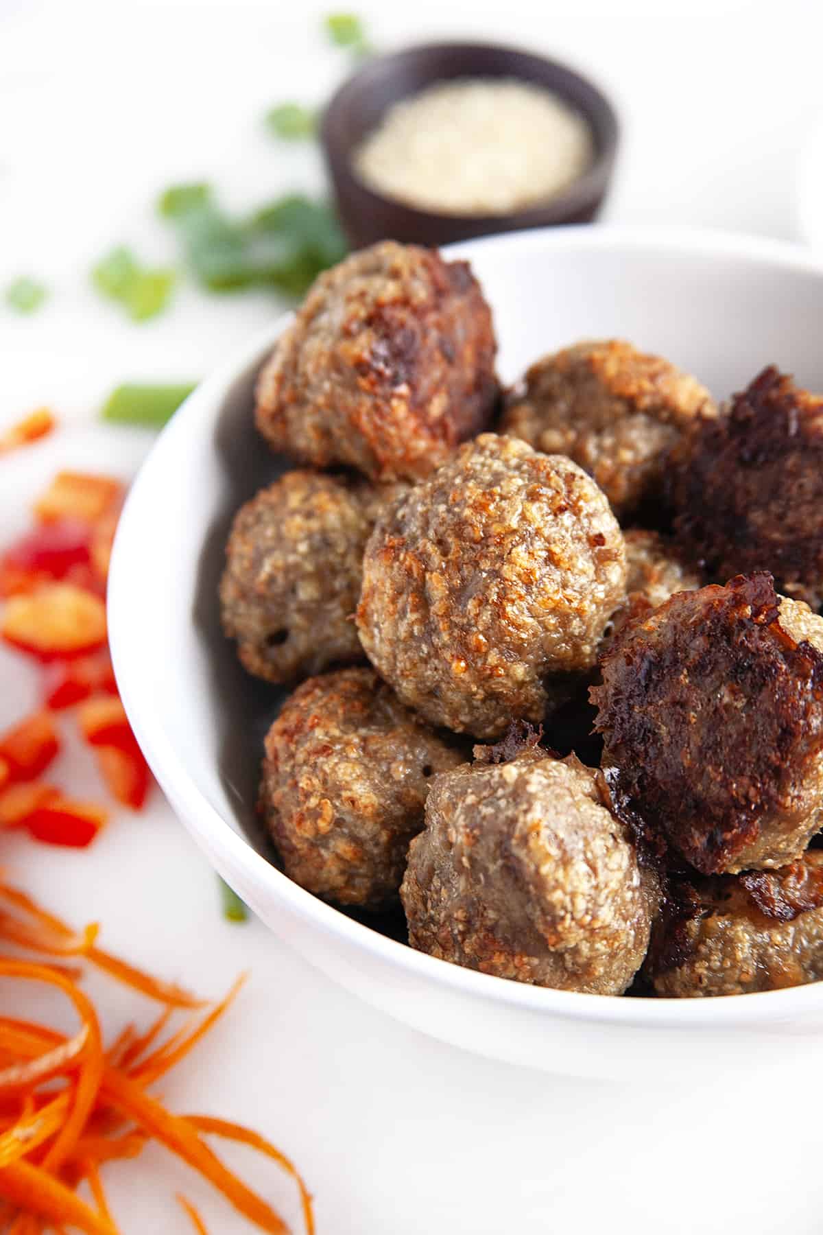 Bowl full of meatballs showing crunchy undersides. 