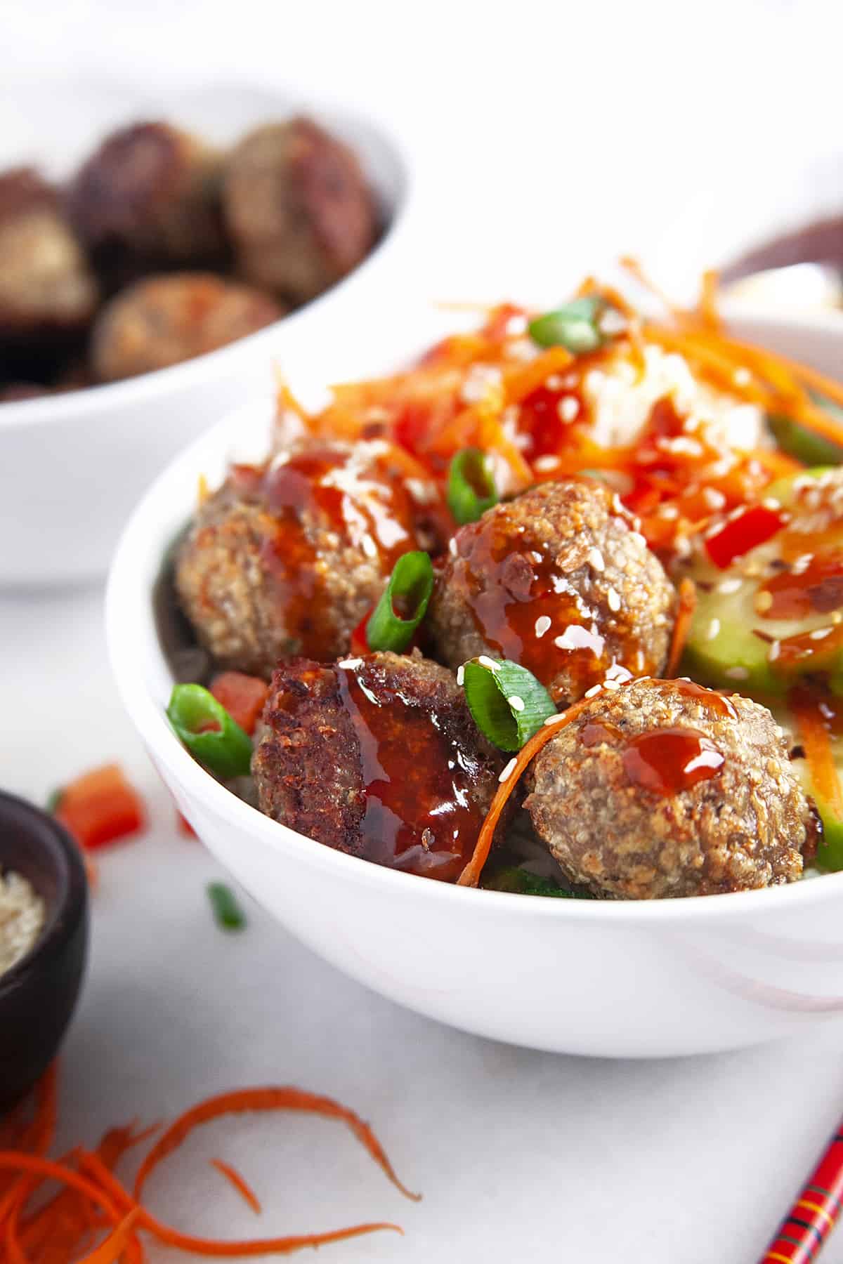 Close-up of chicken meatball in a white bowl with veggies. 