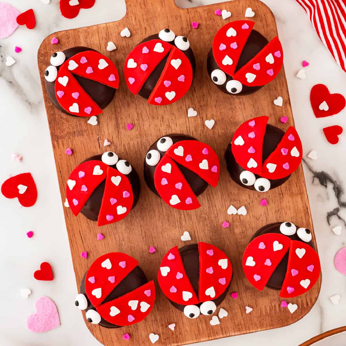 Overhead square photo of love bugs on a wooden board. 