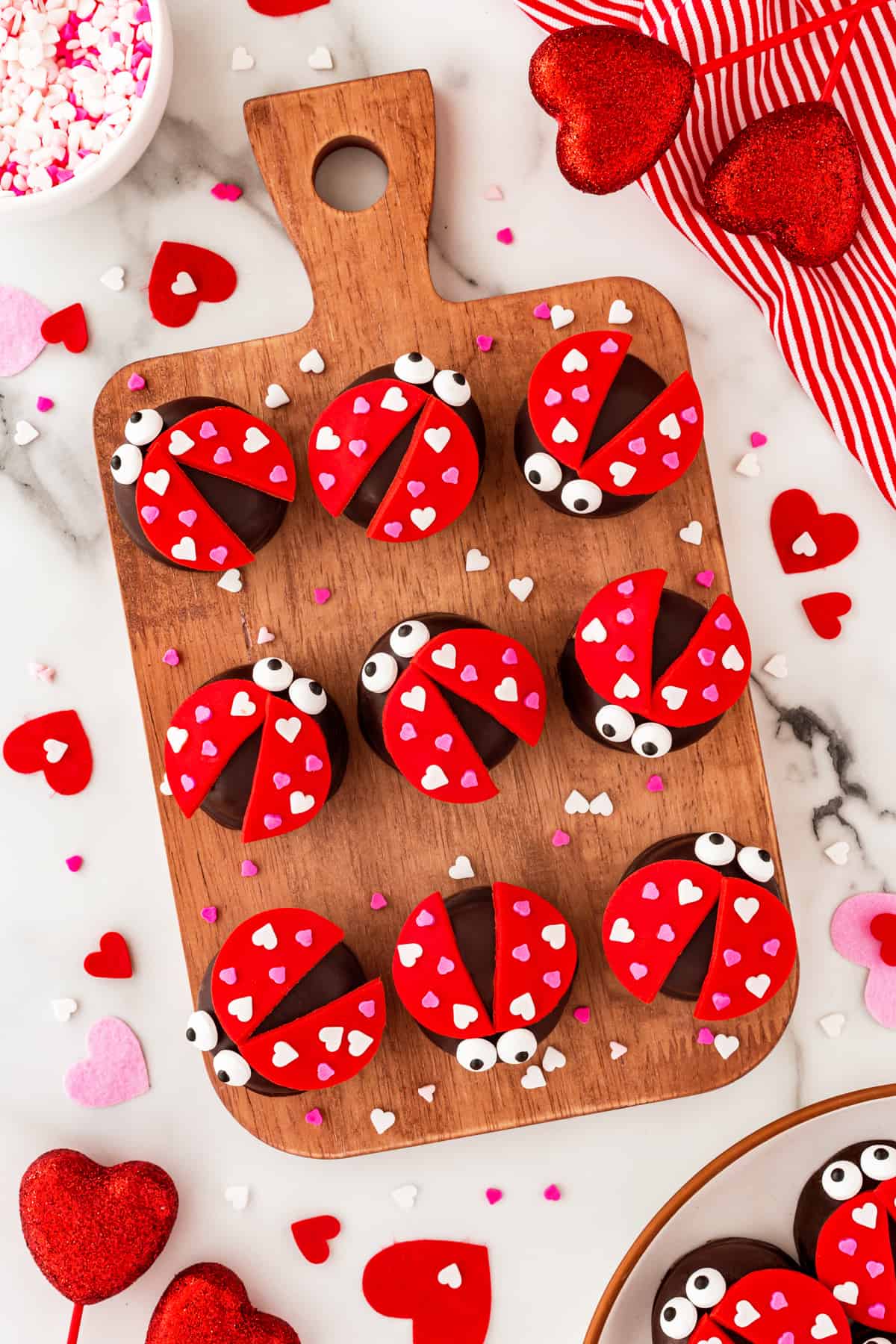 Love bugs on a wooden board with Valentine's Day hearts and large heart confetti around. 
