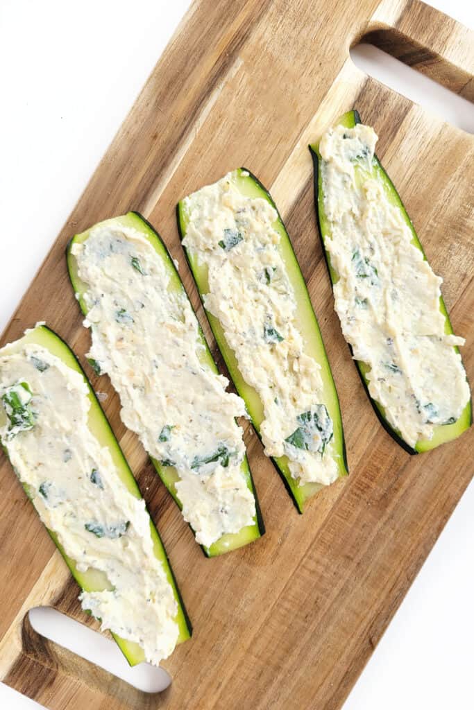 Spreading cheese mixture on zucchini slices. 
