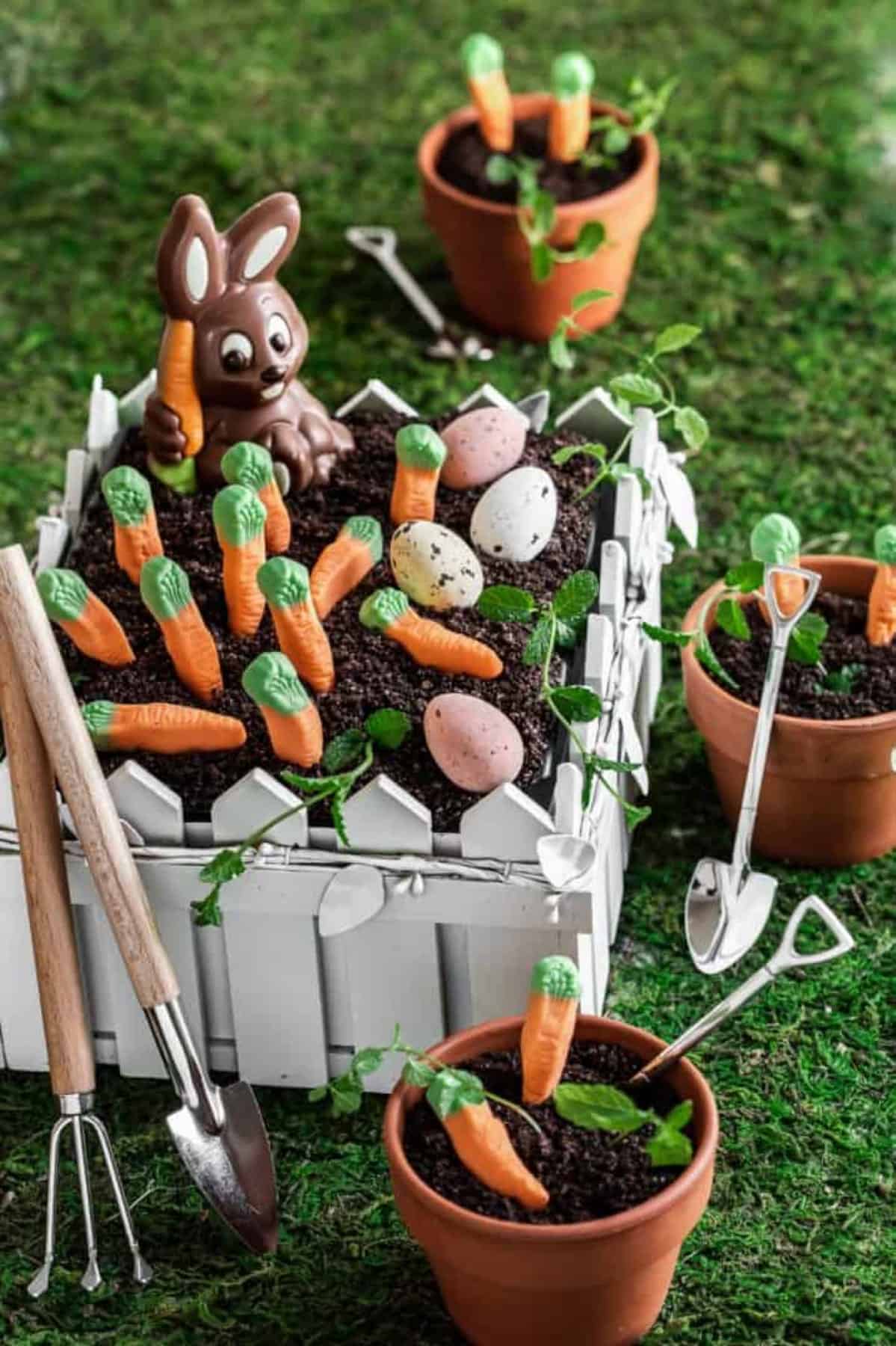 Dirt cake in a fenced container plus little pots with dirt cake too. 