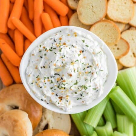 Everything bagel dip with veggies and bagels on a platter.