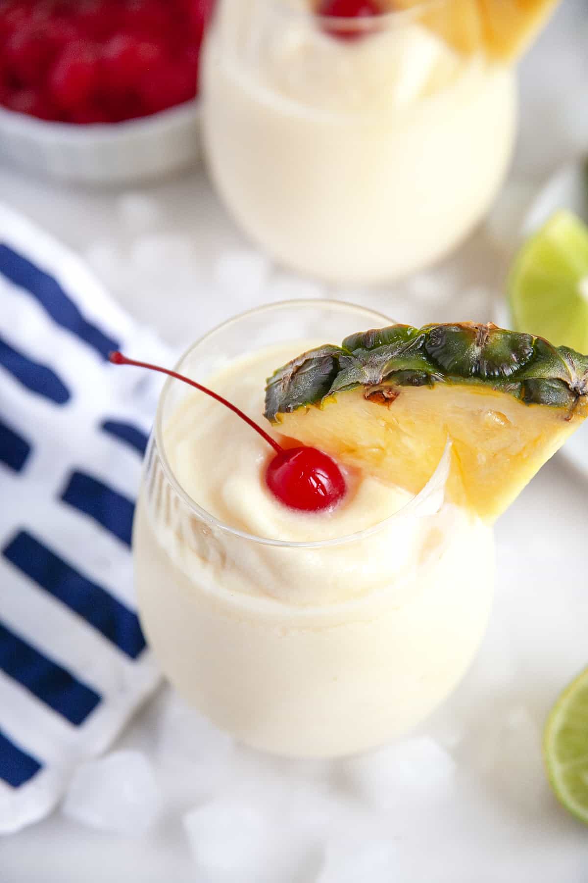 Slight overhead shot of looking into a glass of pina colada with a cherry and pineapple wedge. 