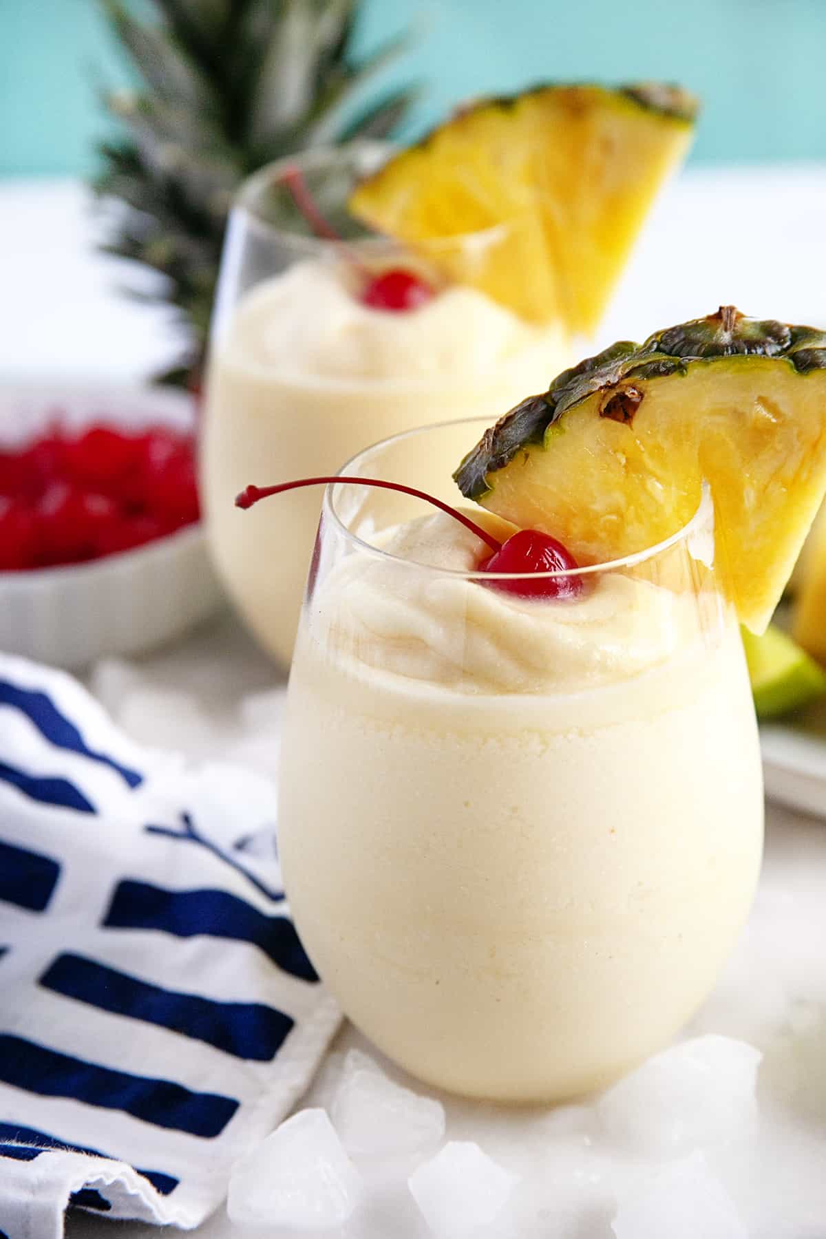 Two pina coladas with cherries and pineapple wedges. 
