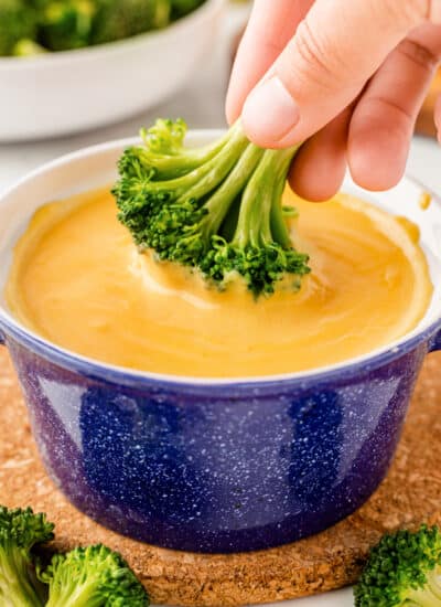 Dipping broccoli into cheese sauce.