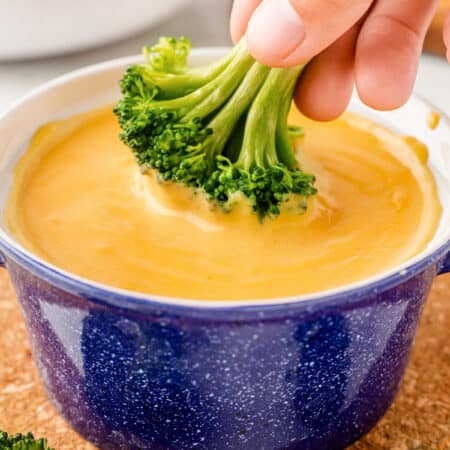 Dipping broccoli into cheese sauce.