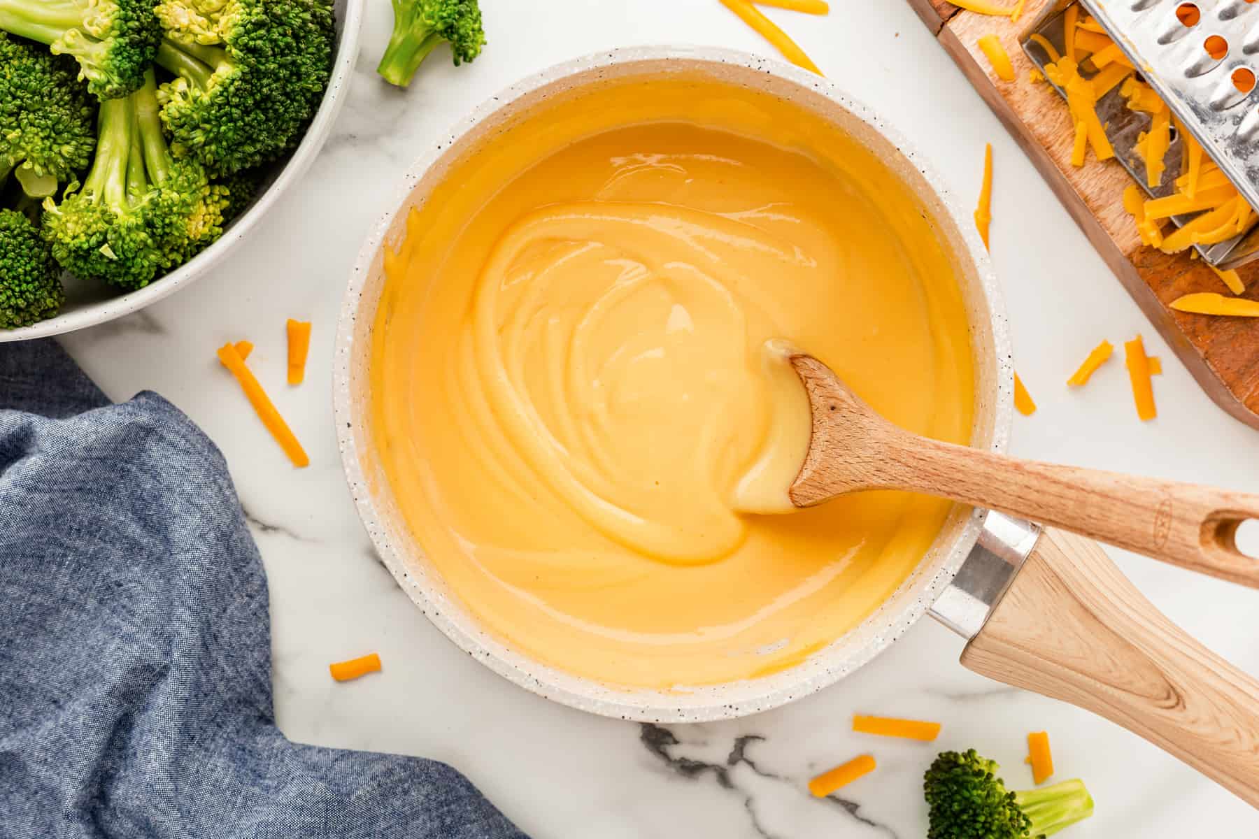 Horizontal cheese sauce in a pot with a wooden spoon. 