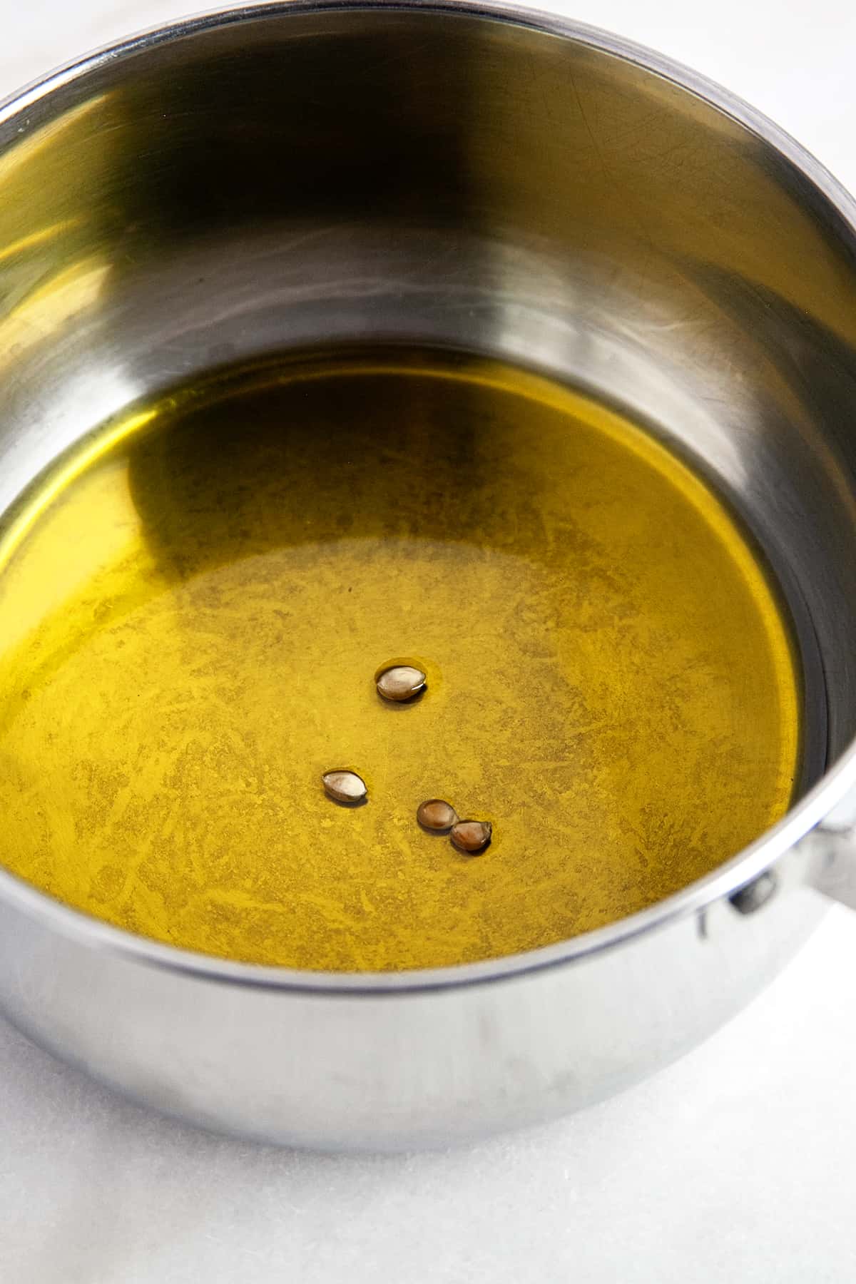 A few popcorn kernels in olive oil in a pot. 