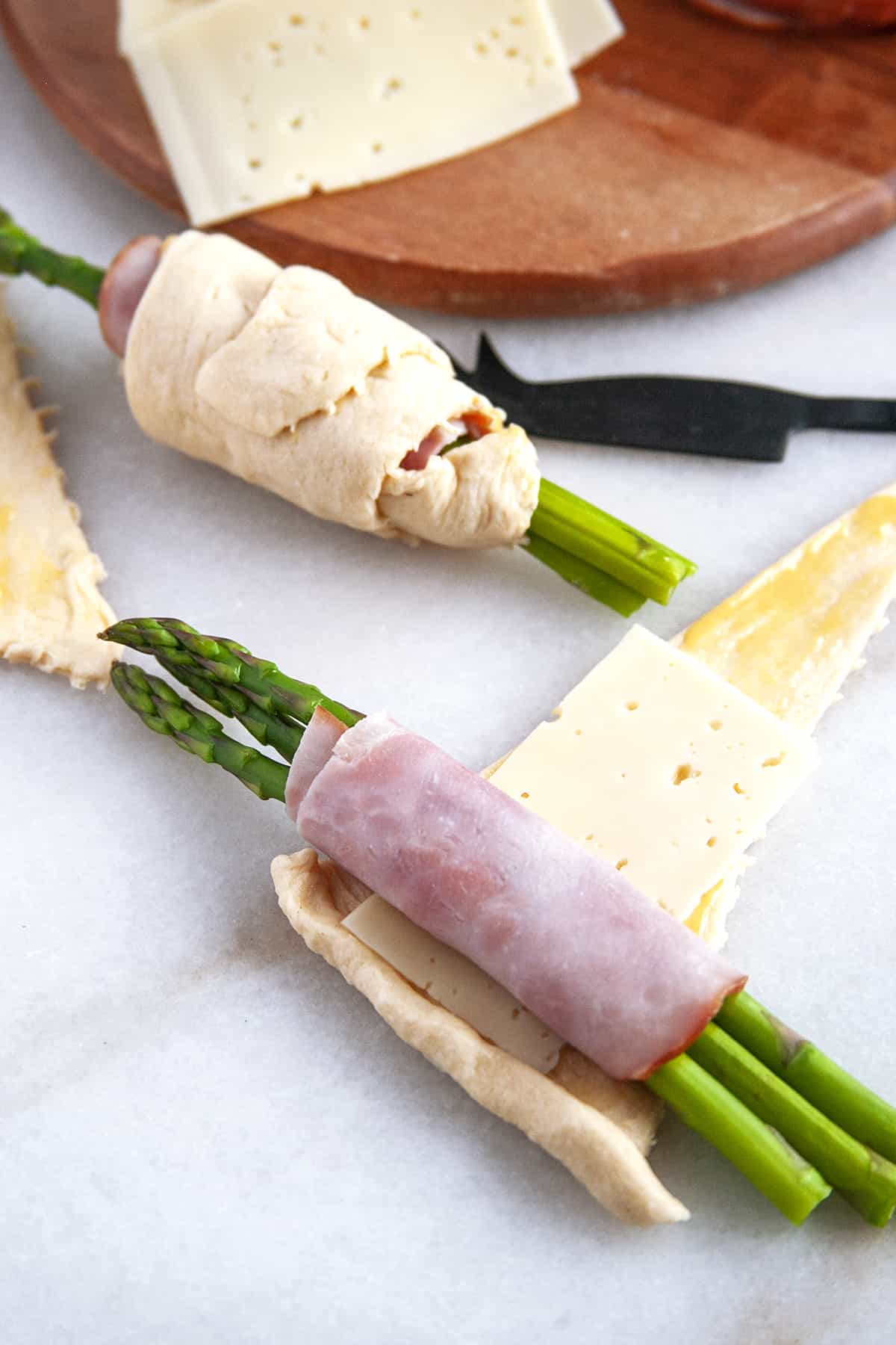 Ham rolled around asparagus ready to be rolled in the crescent roll with cheese. 