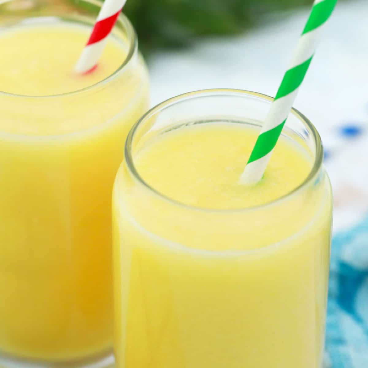 Square photo close up of mango pineapple smoothies with straws. 