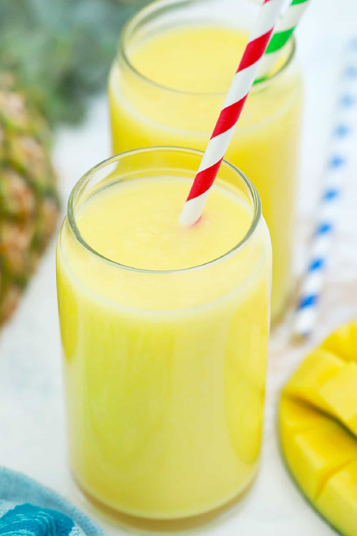 Mango Pineapple Smoothie in a glass with a straw.