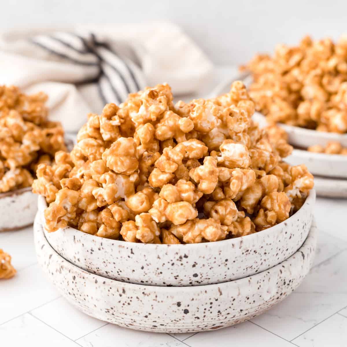 Square photo of caramel corn in stacked bowls. 