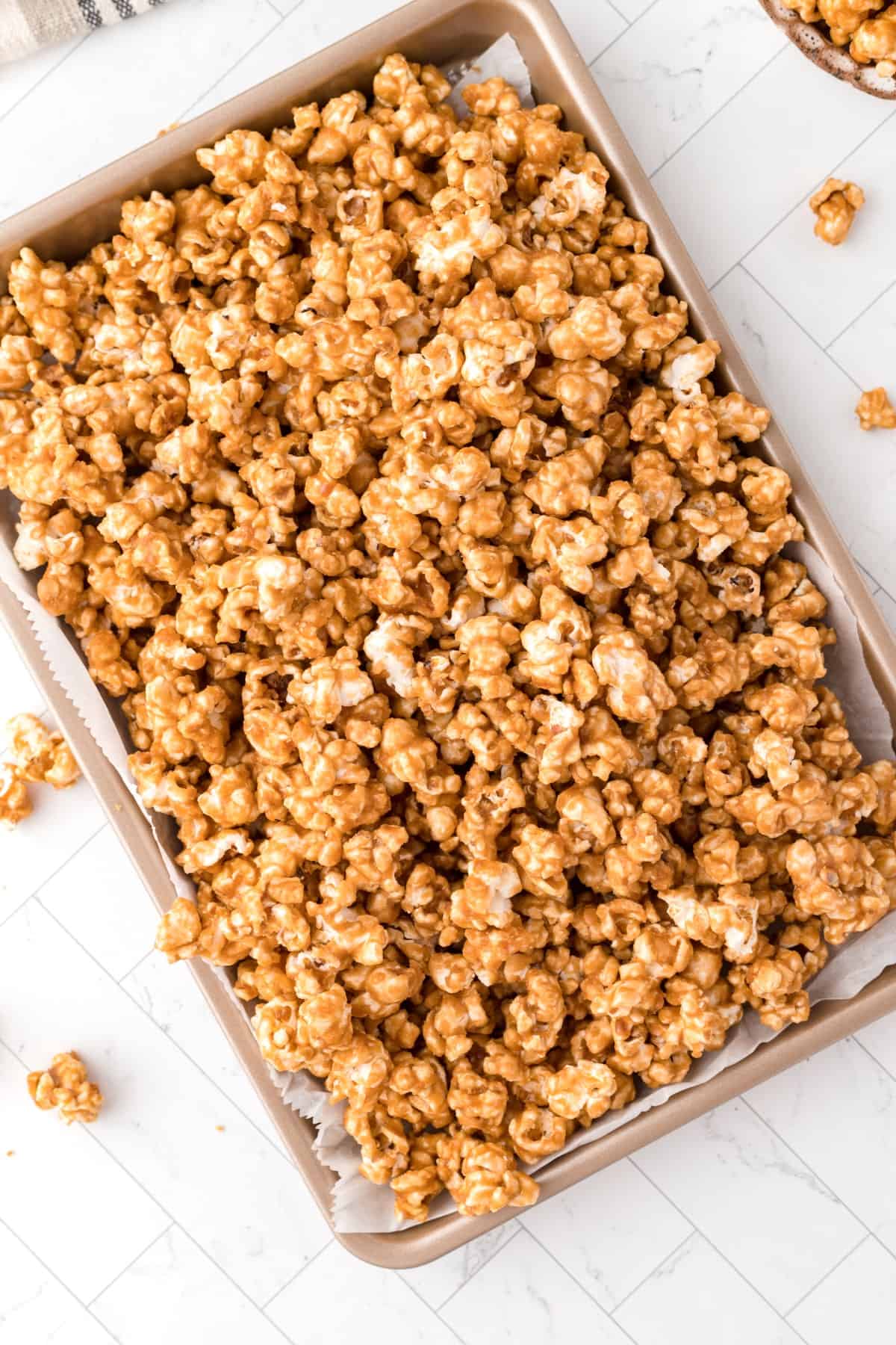 Overhead of caramel popcorn on a baking sheet covered with parchment. 