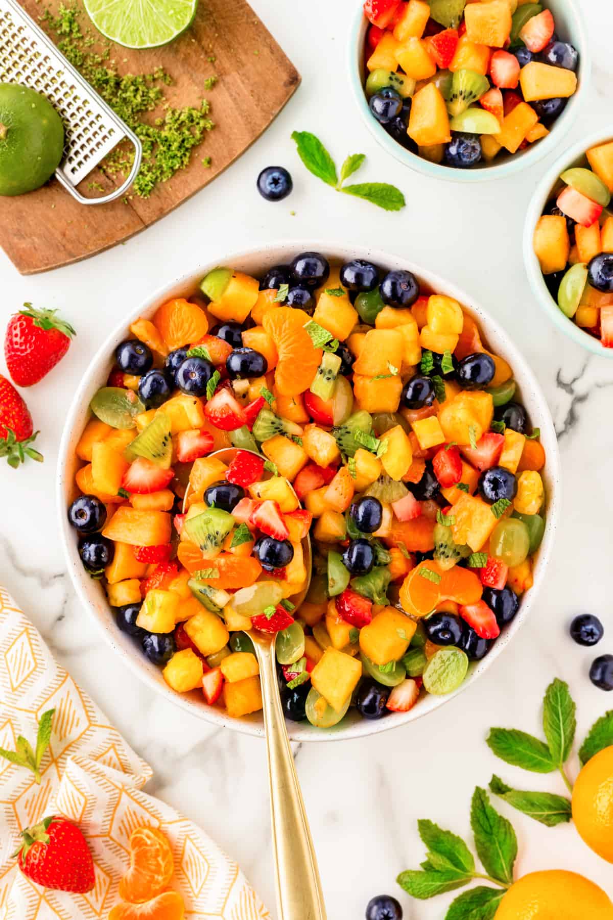 Overhead shot of a fresh fruit salad in a bowl with a spoon. 