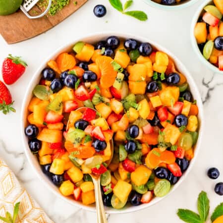 Overhead of a spoon in a bowl of fruit salad.