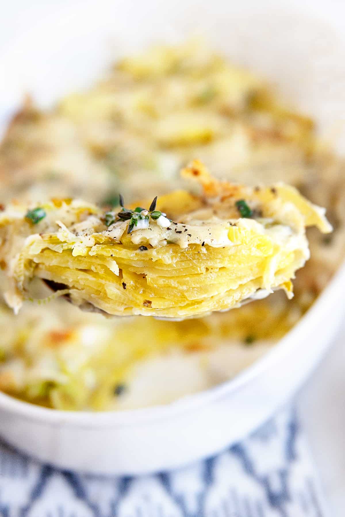 Side view of layers of potato gratin on a large spoon. 