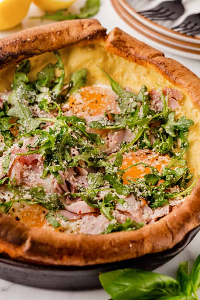 Close-up of the interior of the pancake showing ham, eggs, arugula and sprinkled with Parmesan cheese. 