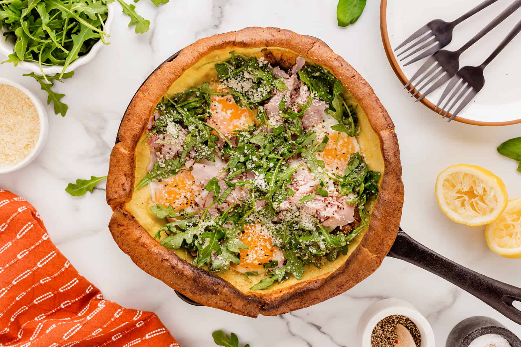 Horizontal picture of a Dutch Baby filled with eggs, ham and arugula salad. 