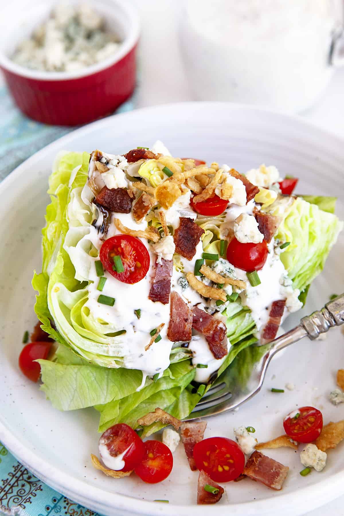 Wedge salad with a fork on a white plate. 