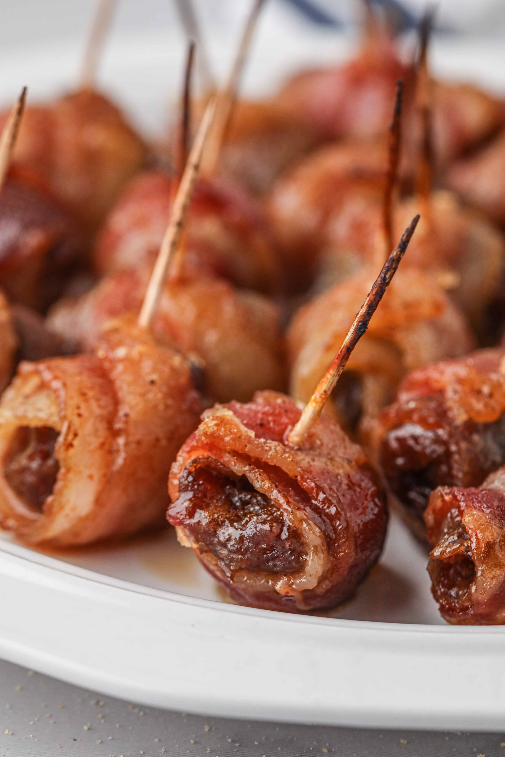 Close-up shot of a juicy, saucy looking bacon-wrapped date. 