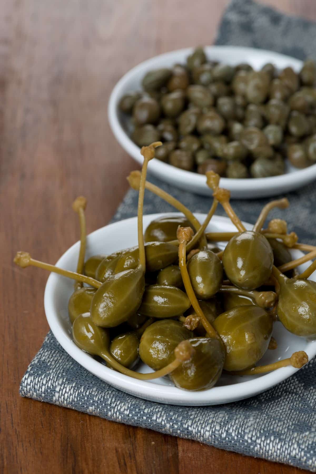 Two kinds of pickled capers, vertical.