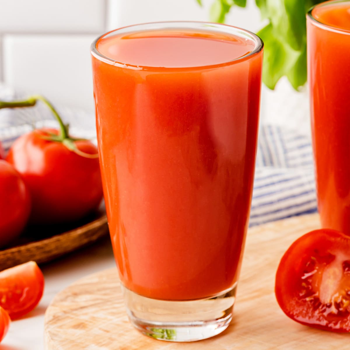 Full glasses of tomato juice with tomatoes around and in the background. 