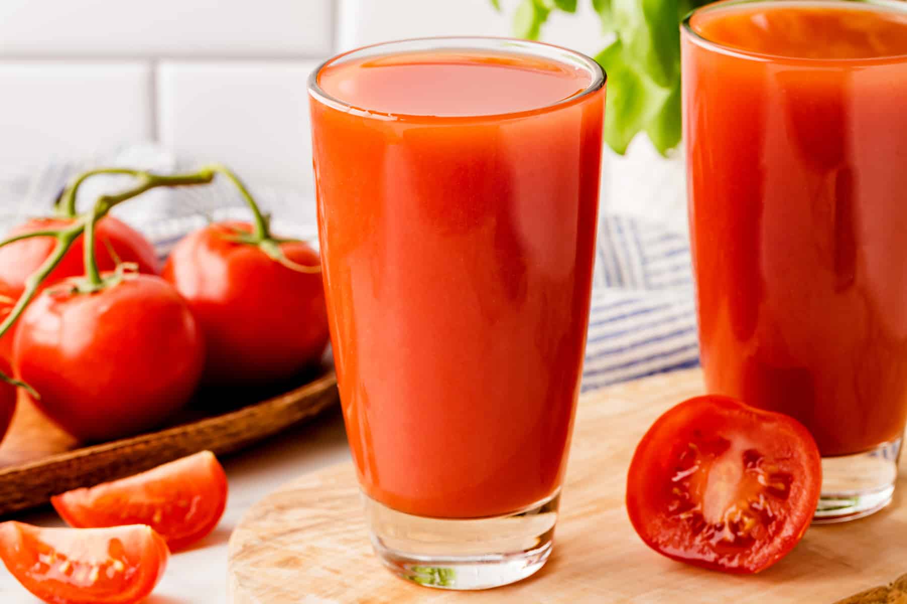 Horizontal picture of full glasses of tomato juice and fresh tomatoes. 