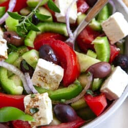 A spoon in a bowl of Greek Salad.