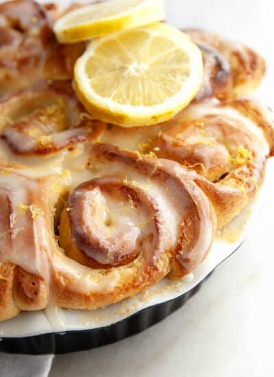Lemon sweet rolls in a baking dish with lemon slices on top.