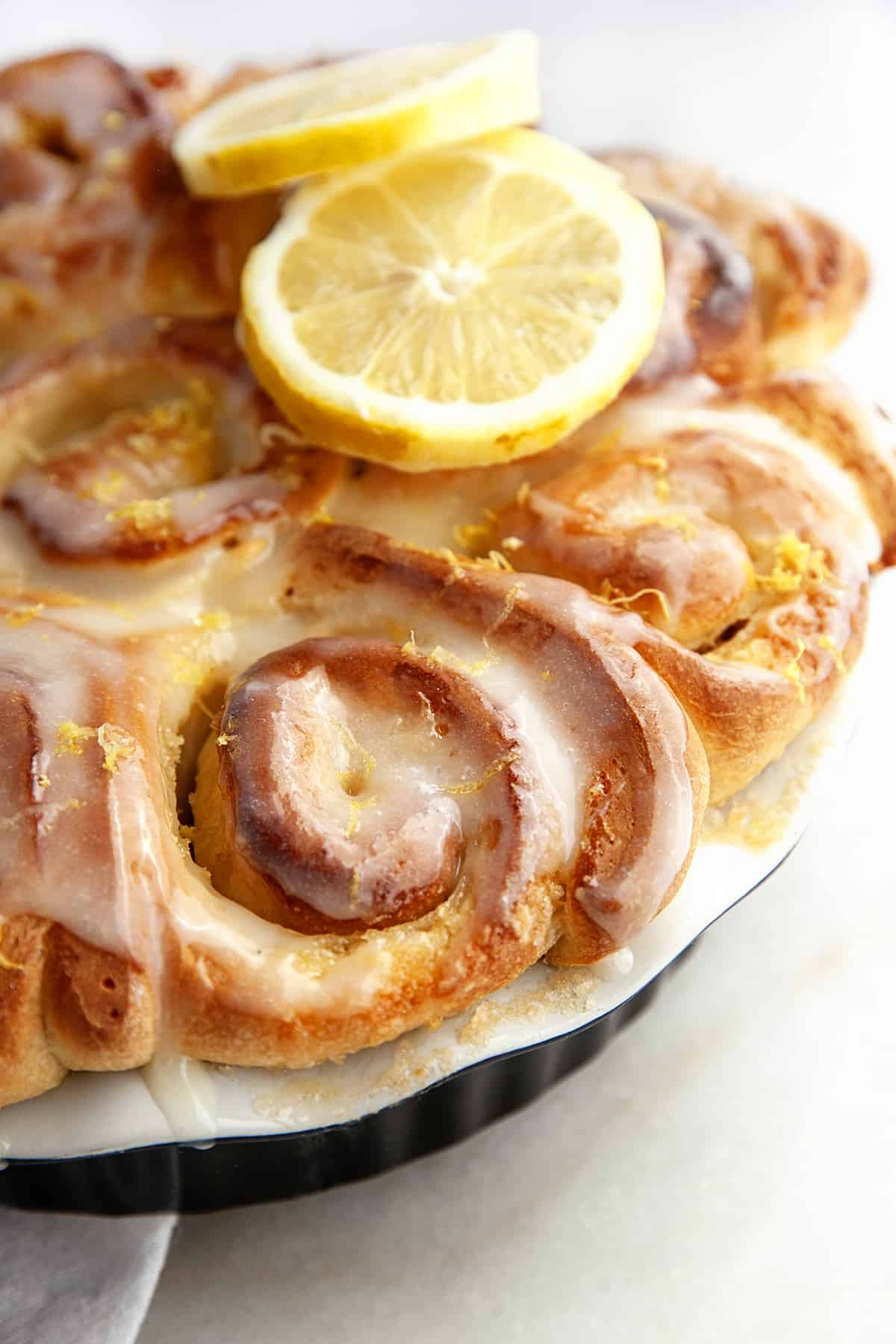 Lemon sweet rolls in a  baking pan clos-up, iced and lemon zest on top. 