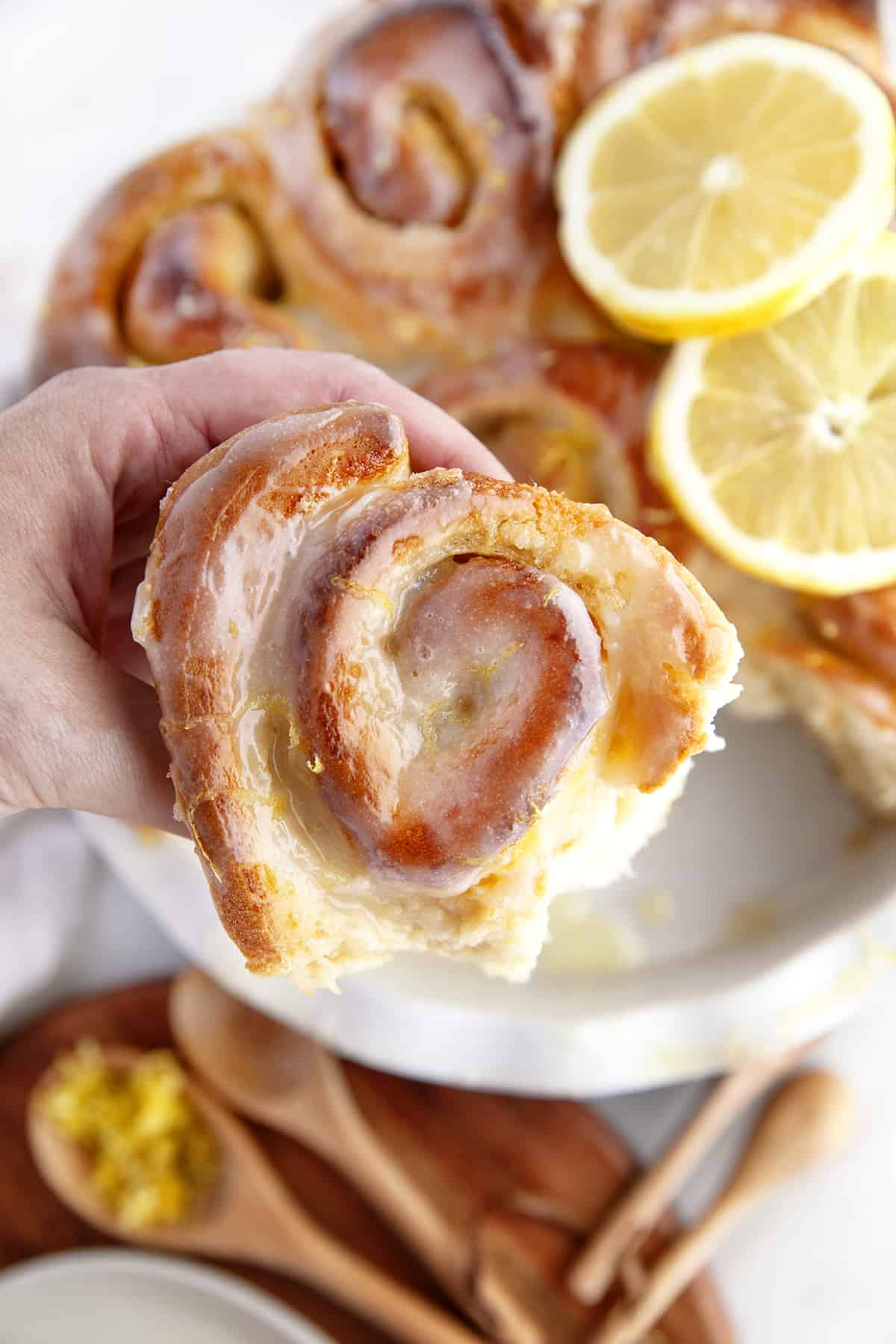 Holding a sweet roll showing lemon zest on top. 