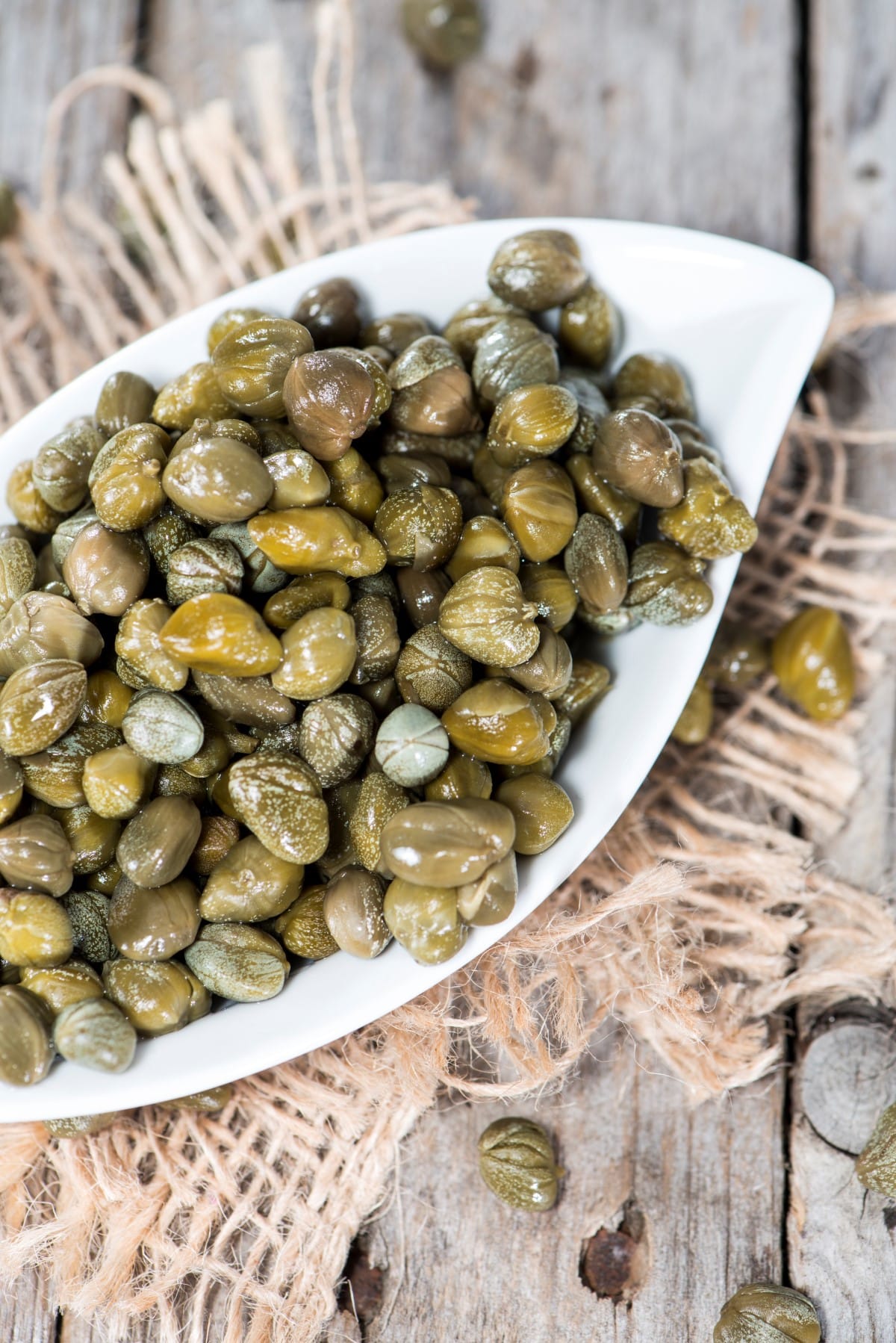 Heap of preserved Capers on vintage background.
